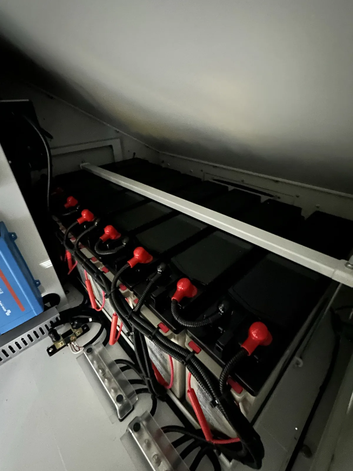 The battery bank: a row of sealed gel batteries with red terminal caps, under a hold-down bar