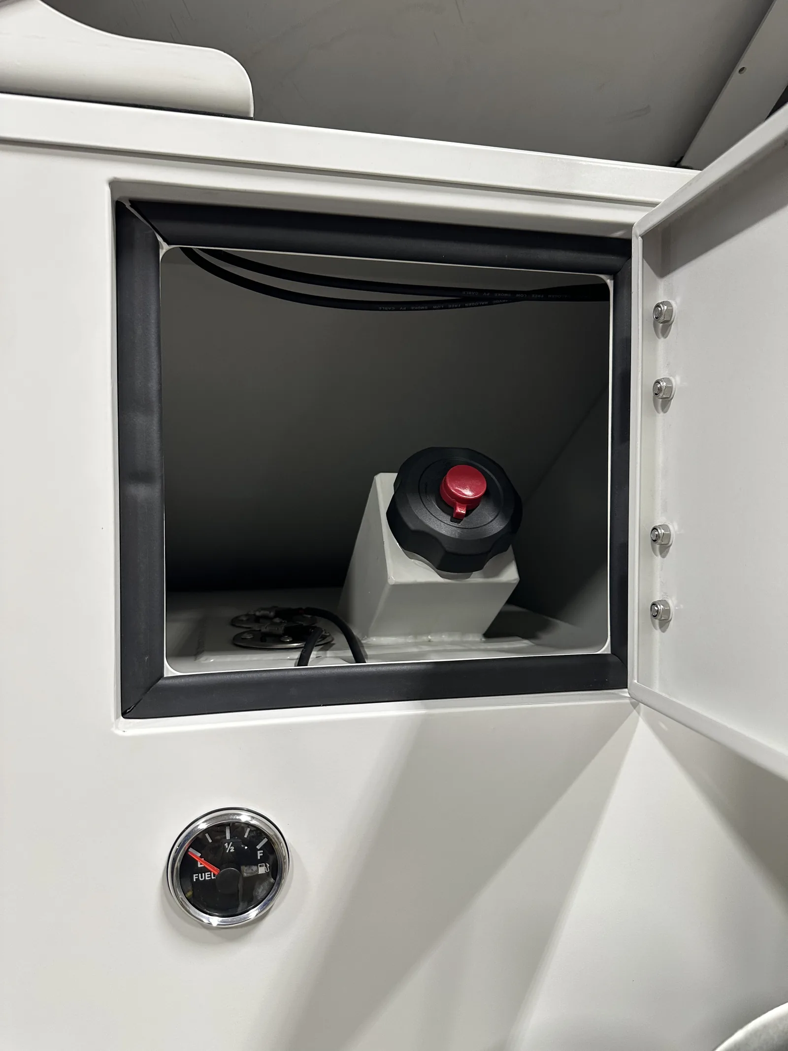 The fuel filler cap for the integrated tank inside its compartment, with the fuel gauge next to the door