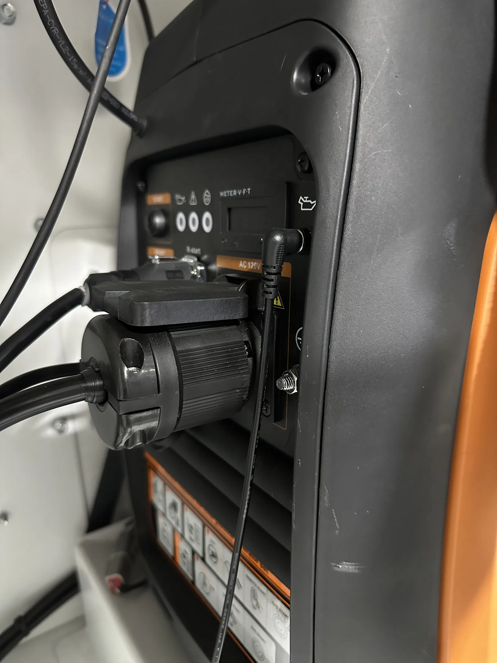 The generator connection panel: power output cord, oil monitor, remote-start cable, and charging cable plugged in