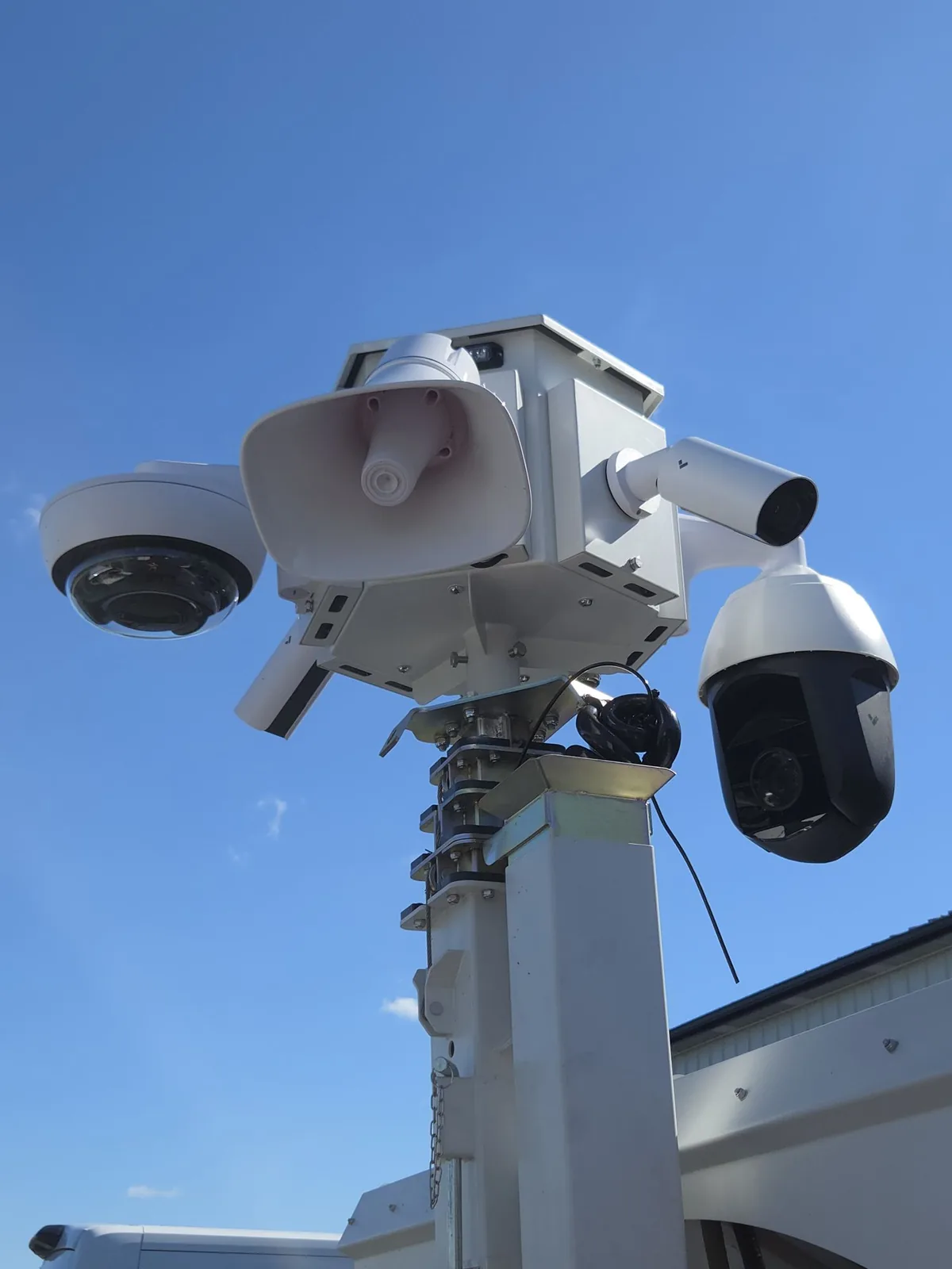 The mast head from below: a dome camera, the speaker horn, a bullet camera, and the PTZ camera around the central enclosure